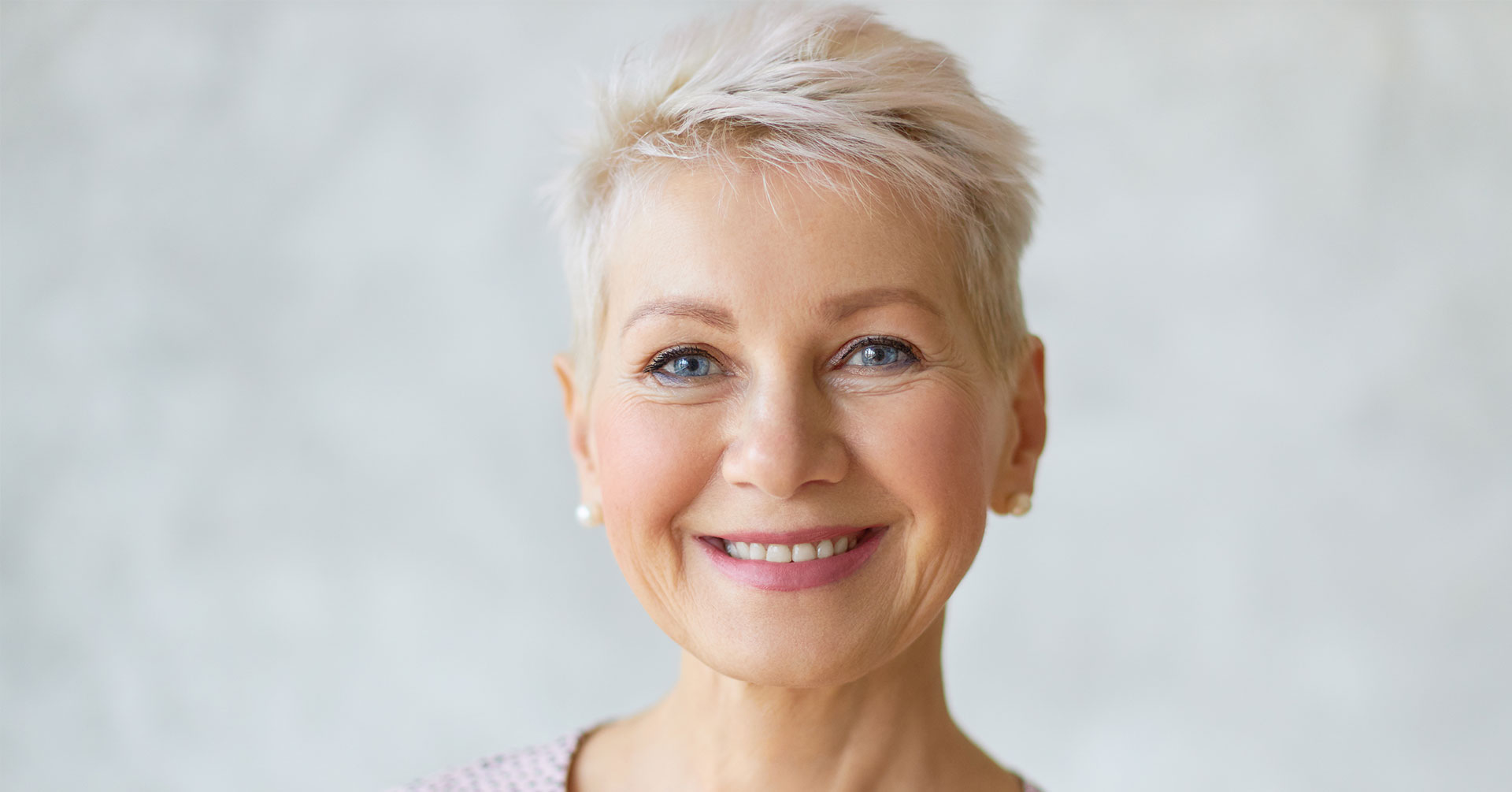 An elderly woman with short hair and a smile, looking directly at the camera.