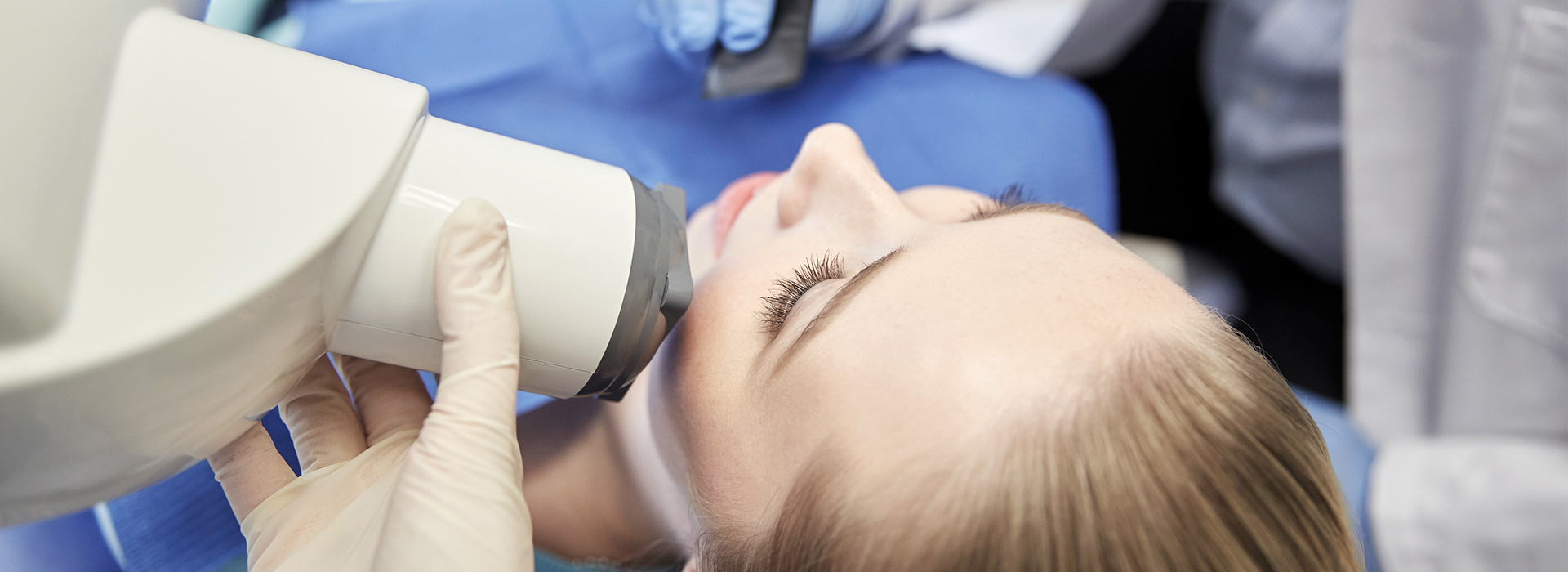 A person receiving a dental examination with a dental mirror and light.