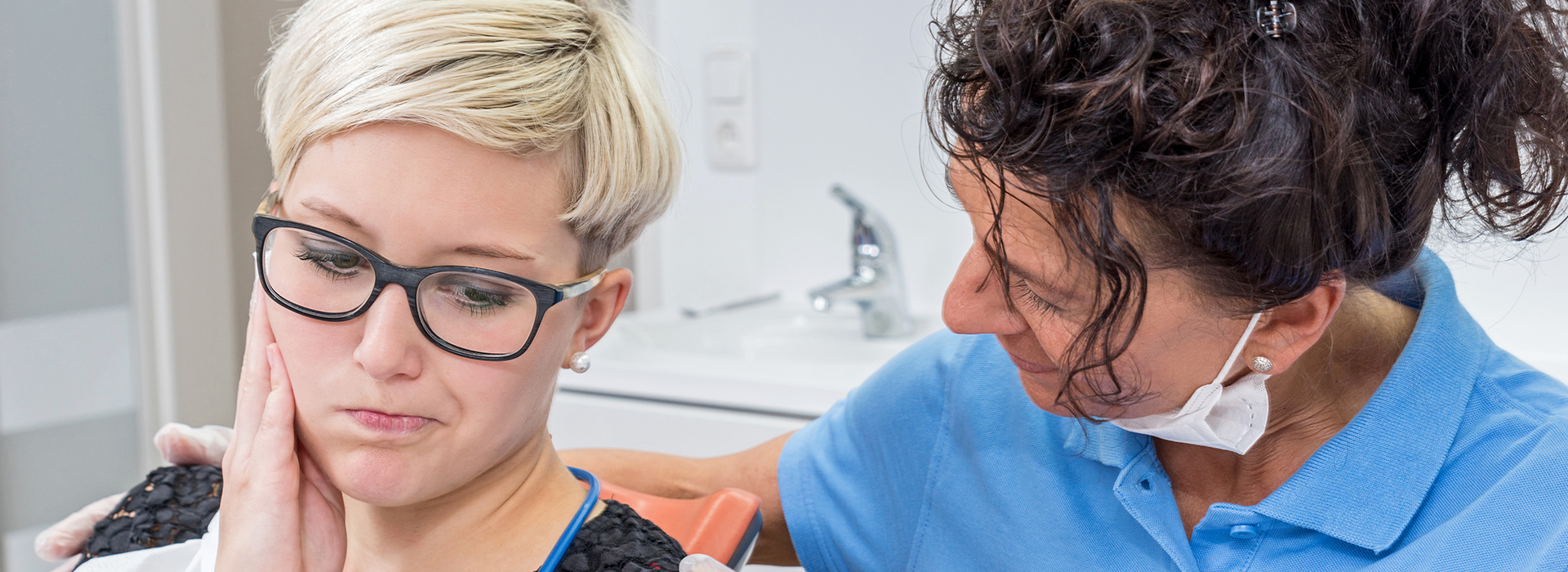 The image shows a person receiving dental care from another individual in what appears to be a dental office setting.