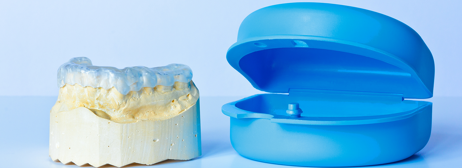 The image shows a close-up of two dental implants, one with a blue protective cover and the other without such a cover.