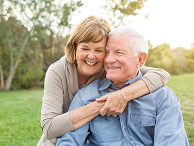 An elderly couple embracing affectionately outdoors.