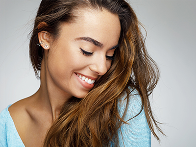 A young woman with long hair, smiling softly, against a blurred background.