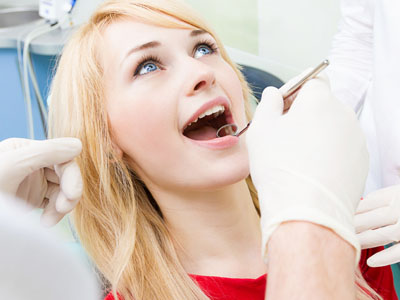 A woman in a dental chair receiving dental care, with a dentist performing the procedure.