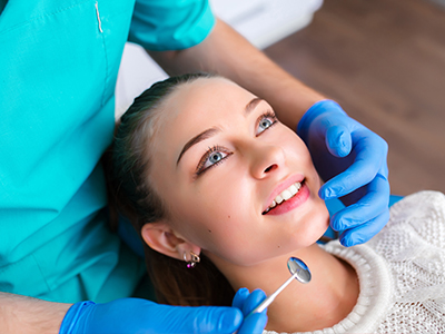 A young woman receiving dental care, with a dentist performing a procedure.