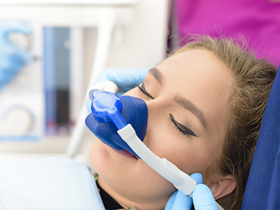 A person receiving an oxygen treatment with a medical device, attended by a healthcare professional.